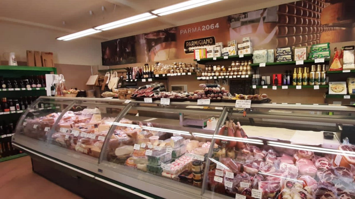 Interno dello spaccio del Caseificio Pongennaro a Soragna, con il banco dei salumi e gli scaffali dei vini

